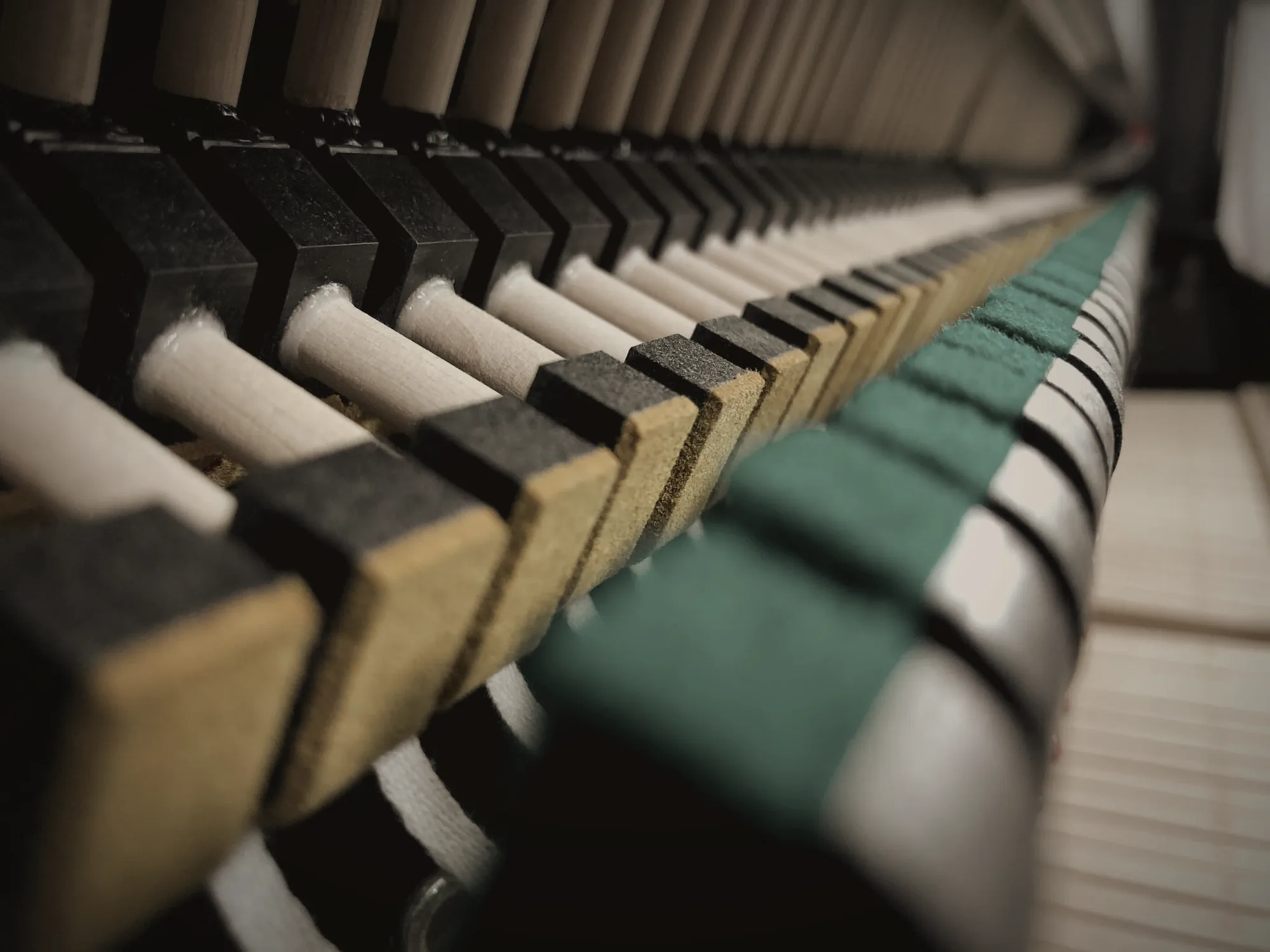 Close-up of an upright piano action with green and black felts