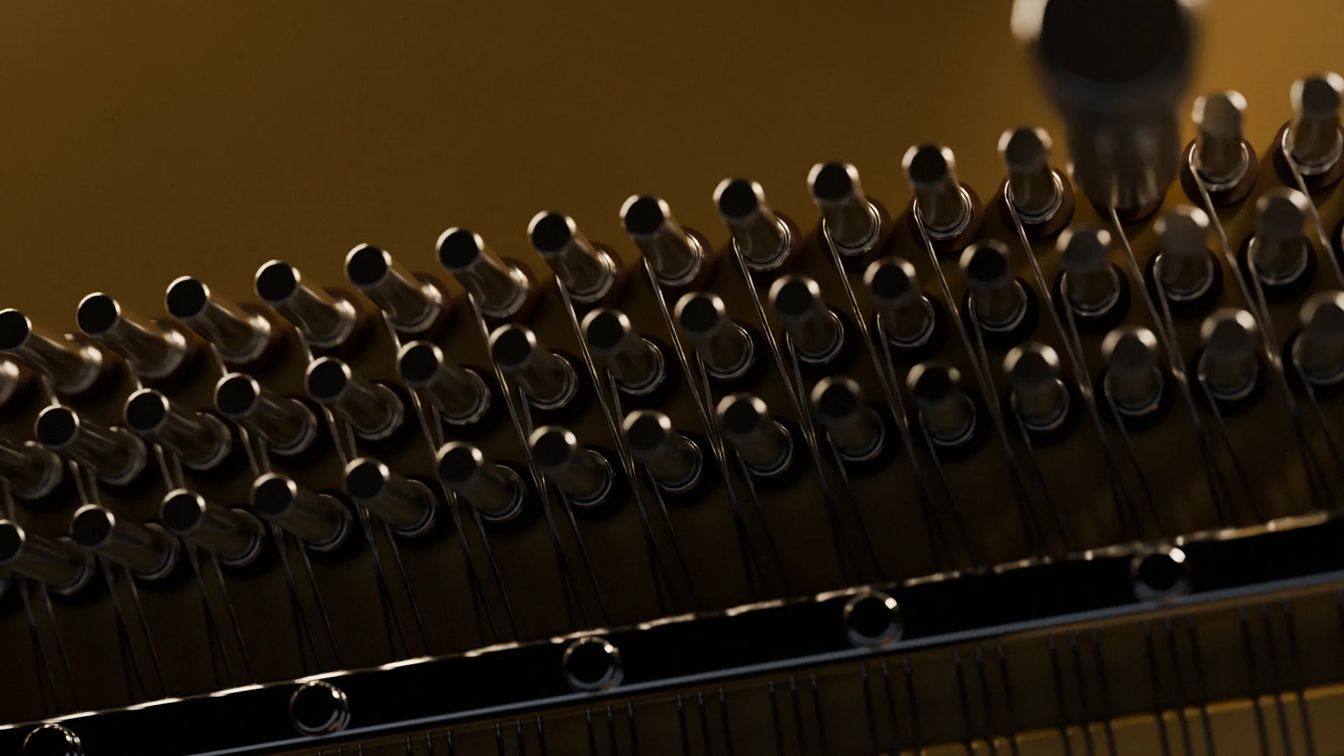 Tuning pins set in a gold piano plate, with a tuning lever fitted to one pin