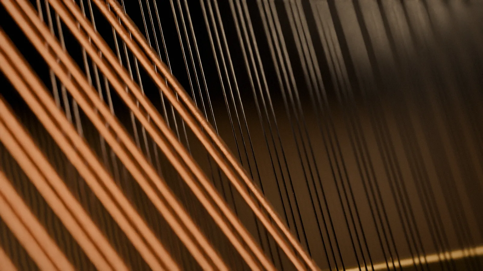 Bass and treble strings inside a piano, lit from the side